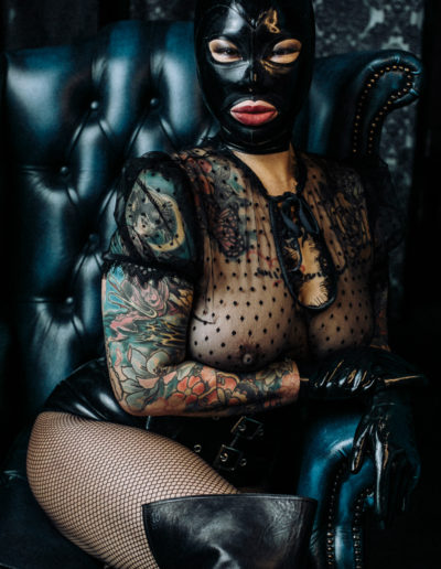 Black latex hood Mistress sitting in leather throne