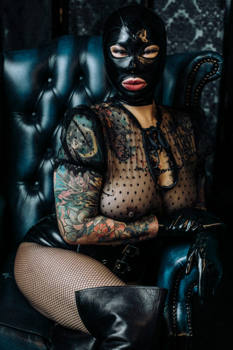 Black latex hood Mistress sitting in leather throne